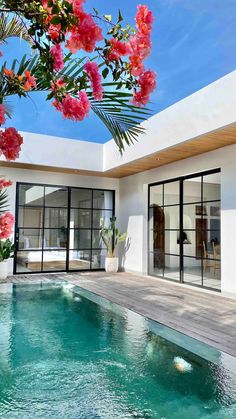 the pool is surrounded by pink flowers and glass doors that lead to an outdoor patio area