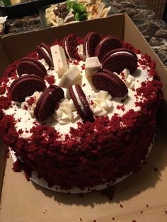 a red velvet cake with white frosting and oreo cookies on top in a box