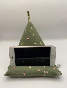 a cell phone sitting on top of a green pillow with a triangle shaped case attached to it