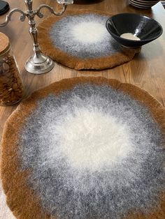 two round rugs sitting on top of a wooden table covered in white and gray wool