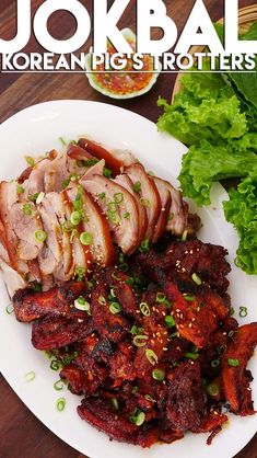 a plate with meat and vegetables on it next to some lettuce in the background