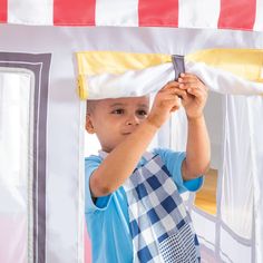 a young boy is playing with a toy house that he made out of cardboard and duct tape