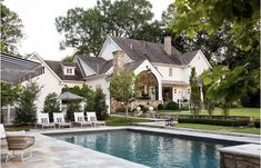 a house with a pool in front of it and lawn furniture around the pool area