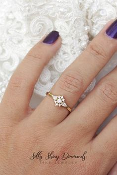 a close up of a person's hand with a ring on her finger and purple nail polish