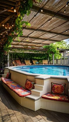 an outdoor swimming pool surrounded by wooden decking and seating with lights strung from the ceiling