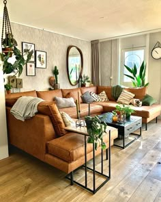 a living room filled with lots of furniture next to a wall mounted clock and potted plants