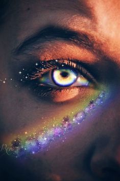 a woman's eye with stars painted on her face and the image of a rainbow