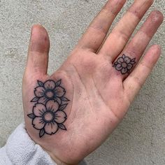 a person's hand with a flower tattoo on the middle of their left palm