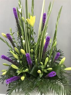 a vase filled with lots of purple and yellow flowers on top of a white table