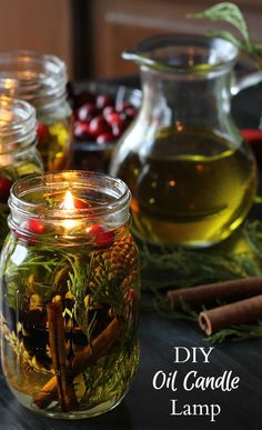 homemade diy oil candle lamp with cinnamons, cranberries and herbs in glass jars