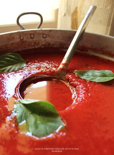 a large pot filled with red sauce and green leaves