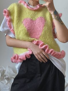 a woman taking a selfie while wearing a sweater with pink hearts on it and holding a cell phone up to her ear