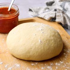 a ball of bread sitting on top of a wooden cutting board next to a jar of ketchup