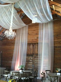 the inside of a restaurant with tables and chairs covered in white draping, chandelier and table cloths