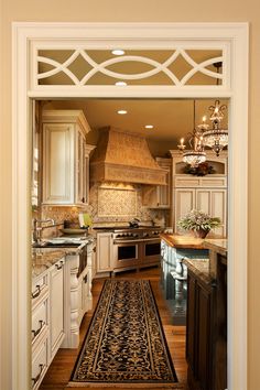 an open door leading to a kitchen with white cabinetry and wood flooring on both sides