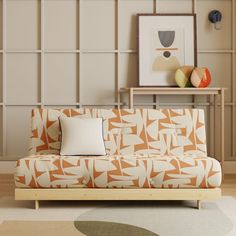 an orange and white couch sitting on top of a wooden floor next to a table