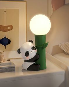 a panda bear lamp sitting on top of a white table next to a green tree