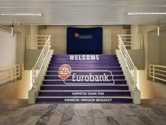 the entrance to eurobank's office building is lit up with blue and white stairs