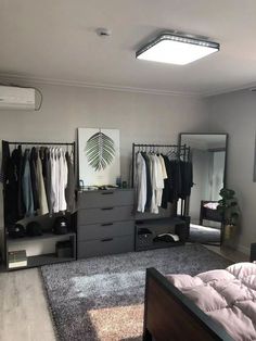 a bedroom with clothes hanging on the wall and a bed in front of two dressers