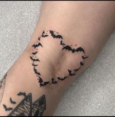 a tattoo with bats flying around it on someone's left arm and the bottom half of his leg