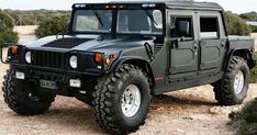 a black hummer truck parked on top of a dirt field