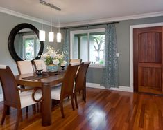 a dining room table with chairs and a mirror on the wall