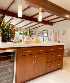 a wine cooler in the middle of a kitchen with wood cabinets and white counter tops