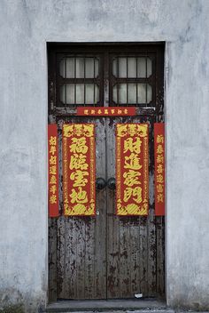 an old wooden door with two red and yellow banners on the front, in chinese