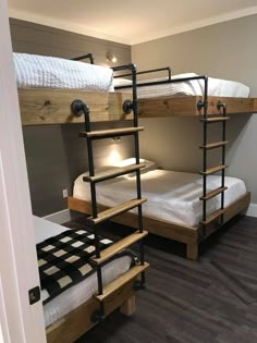 bunk beds with ladders are in a room that has wood floors and gray walls