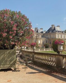 an outdoor patio with tables and chairs in front of a large building that has pink flowers on it