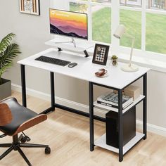 a desk with a computer on it in front of a window and a chair next to it