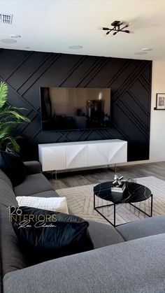 a modern living room with black and white furniture, large flat screen tv on the wall