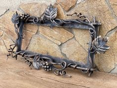 a metal frame sitting on top of a wooden table next to a stone wall covered in leaves