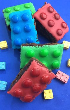 three pieces of cake with legos on them sitting on a blue surface next to small plastic blocks