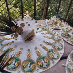 peacock feathers and brooches are sitting on a white tablecloth with gold trim