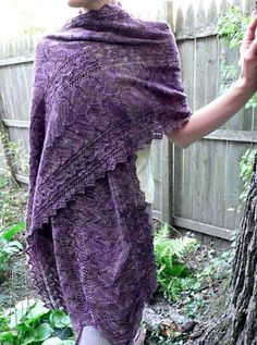 a woman wearing a purple shawl standing next to a tree