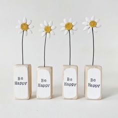 three wooden blocks with daisies in them and the words be happy written on them