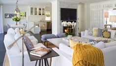 a living room with white couches and yellow throw pillows on the back of them