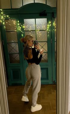 a woman taking a selfie in front of a door with christmas lights on it