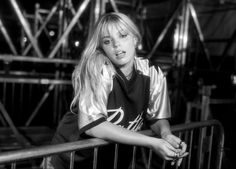 a black and white photo of a woman leaning on a railing with her hand on her hip