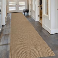 a hallway with a rug on the floor next to a door and a bench in front of it