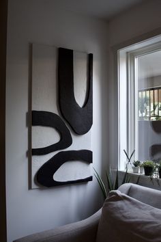 a living room filled with furniture and a painting hanging on the wall above a window