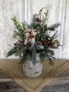 a vase filled with greenery and pine cones on top of a burlock