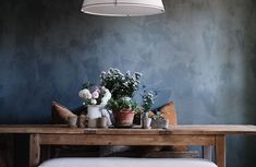 a wooden table topped with potted plants next to a white light hanging from the ceiling