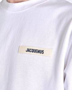 Jacquemus men's logo t-shirt in white. This shirt features a crew neckline, short sleeves and a logo tag at the left chest. Tshirt Message Ideas, Merchandise Ideas Clothing, Shirt Label Design, Off White Tshirt, Tshirt Branding, Street Style Shirt, Vintage Shirt Design, T Shirt Label, Text Tshirt