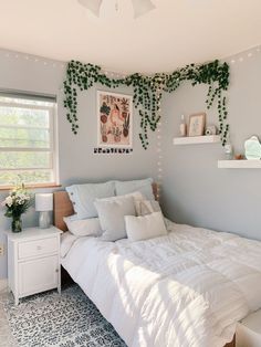 a white bed sitting in a bedroom next to a window with ivy growing on it