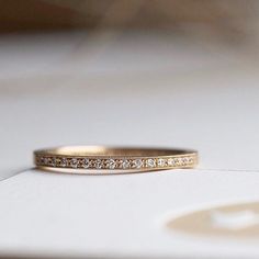 a gold wedding band with small diamonds on the inside and outside, sitting on a white surface