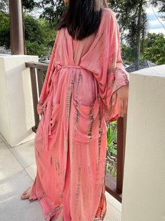 Lightweight and breathable with its gorgeous oversized length, the Swan - Peach Pink Kimono Robe is a must-have with its vibrant color. This relaxed design features a gorgeous tie-dye print paired with a chic waist tie. side pockets and elegant side slits. Layer it on over your favorite outfit for an effortless pop of color. Features: Lightweight feel Very comfortable and breathable Tie-dye Handmade Oversized fit Long sleeves Removable waist tie closure Two pockets Side slits at the hem Size + F Elegant Boho Outfit, Oversized Kimono, Tie Dye Kimono, Bridesmaid Kimono, Robe For Women, Kaftan Designs, Pink Kimono, Mode Kimono, Kimono Robes