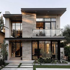 a modern house with large windows and lots of greenery