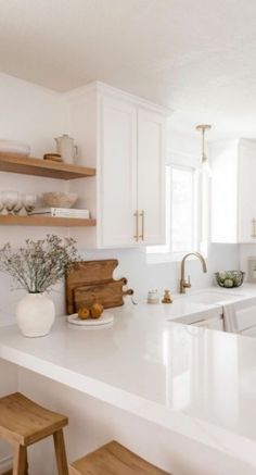 a kitchen with white counter tops and wooden stools